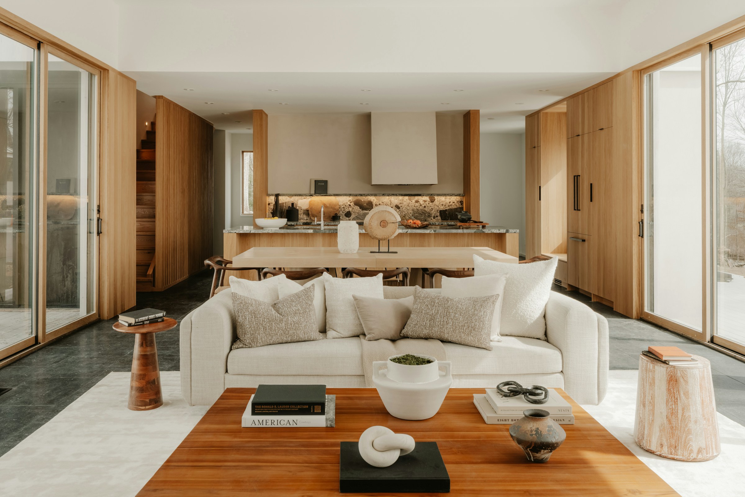 An expansive lounge area with low-profile bouclé seating, curved plaster accents, and an organic travertine coffee table